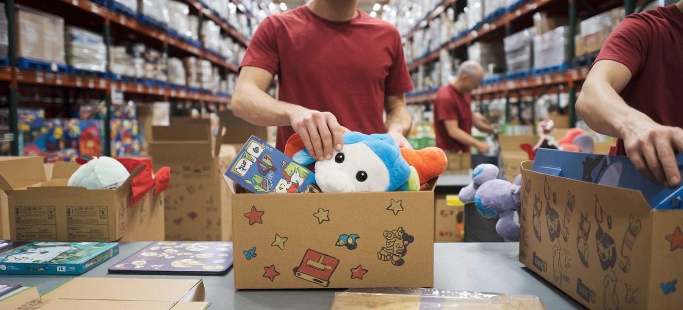 ProShip3PL workers in a fulfillment warehouse carefully packaging toys and games, including board games, plush toys, and electronics. The image highlights the efficient and secure handling of toys, ensuring they are ready for delivery in eco-friendly packaging with playful designs.